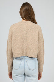 A model wearing the Billie Jean Cardi in colour Oat, from the back