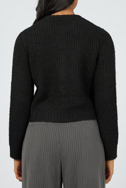 A model wearing the Aya Cardigan in colour Black (Black), from the back