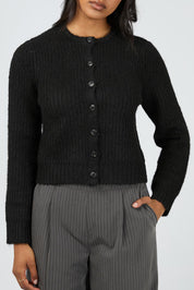 A model wearing the Aya Cardigan in colour Black (Black), from the front, cropped image