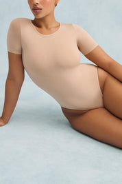 A model wearing the Shelf Bra Tin colourShirt Bodysuit - Rosebeige, from the front, cropped image