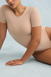 A model wearing the Shelf Bra Tin colourShirt Bodysuit - Rosebeige, from the front, cropped image