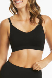 A model wearing the Bare Essentials Support Wirefree Bra in colour Black, from the front, cropped image