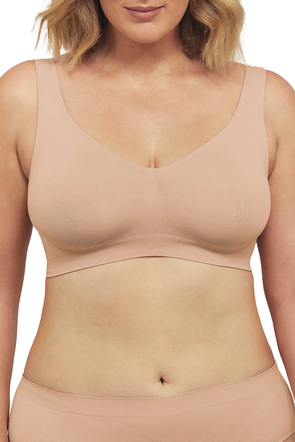 A model wearing the Bare Essentials Shaper Bra in colour Rosebeige, from the front, cropped image