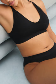 A model wearing the Pure Basics Triangle Modal Bralette in colour Black (Black), from the front, cropped image