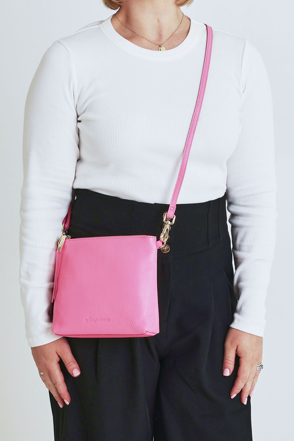 Model Steph wearing size OneSize of the Alexis Leather Crossbody in colour Blossom (Pink), from the front, cropped image