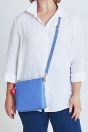 Model Steph wearing size OneSize of the Alexis Leather Crossbody in colour Cornflower (Blue), from the front, cropped image