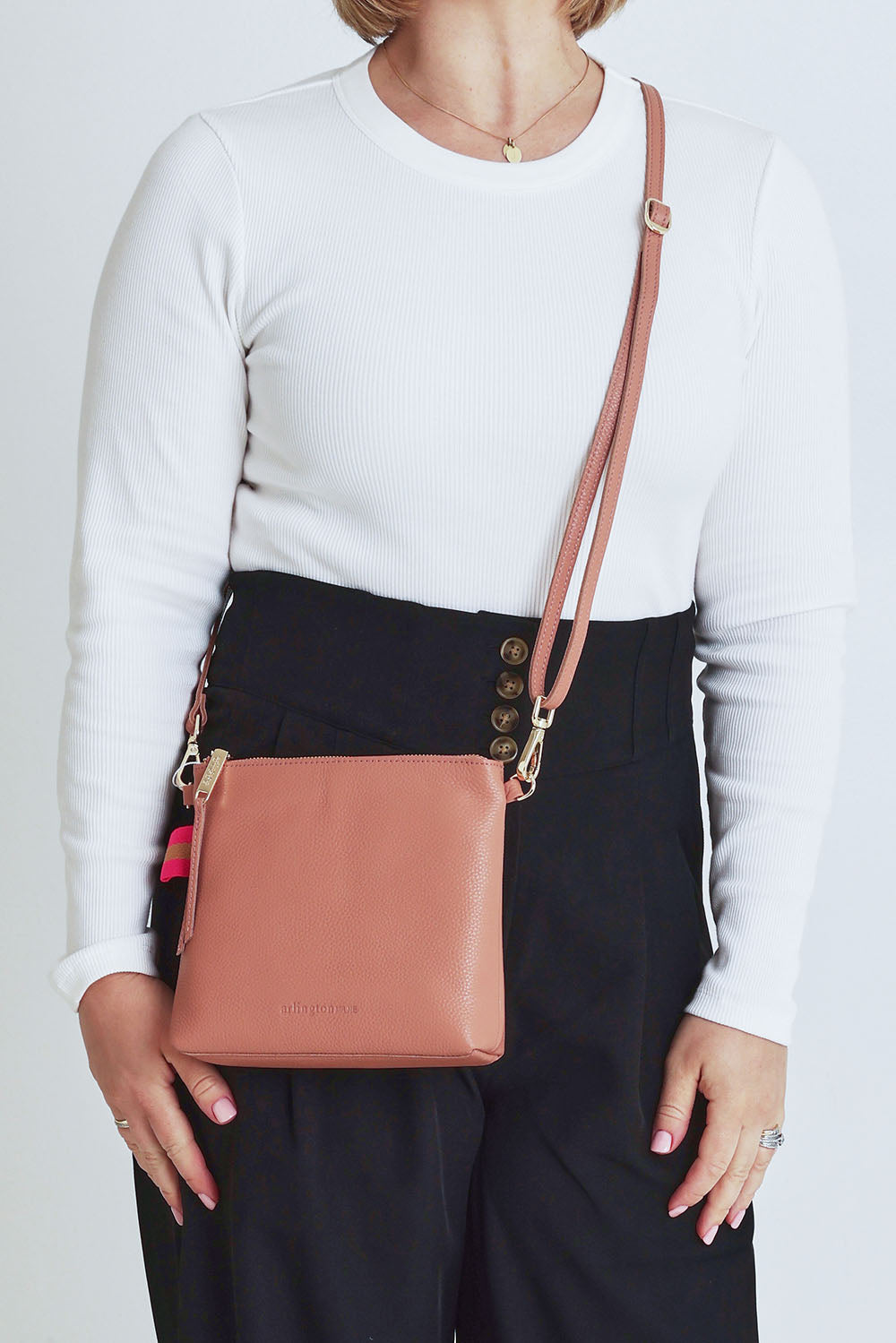 Model Steph wearing size OneSize of the Alexis Leather Crossbody in colour Rosette (Pink), from the front, cropped image