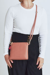 Model Steph wearing size OneSize of the Alexis Leather Crossbody in colour Rosette (Pink), from the front, cropped image