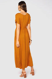 A model wearing the Mila Maxi Dress in colour Tumeric, from the back