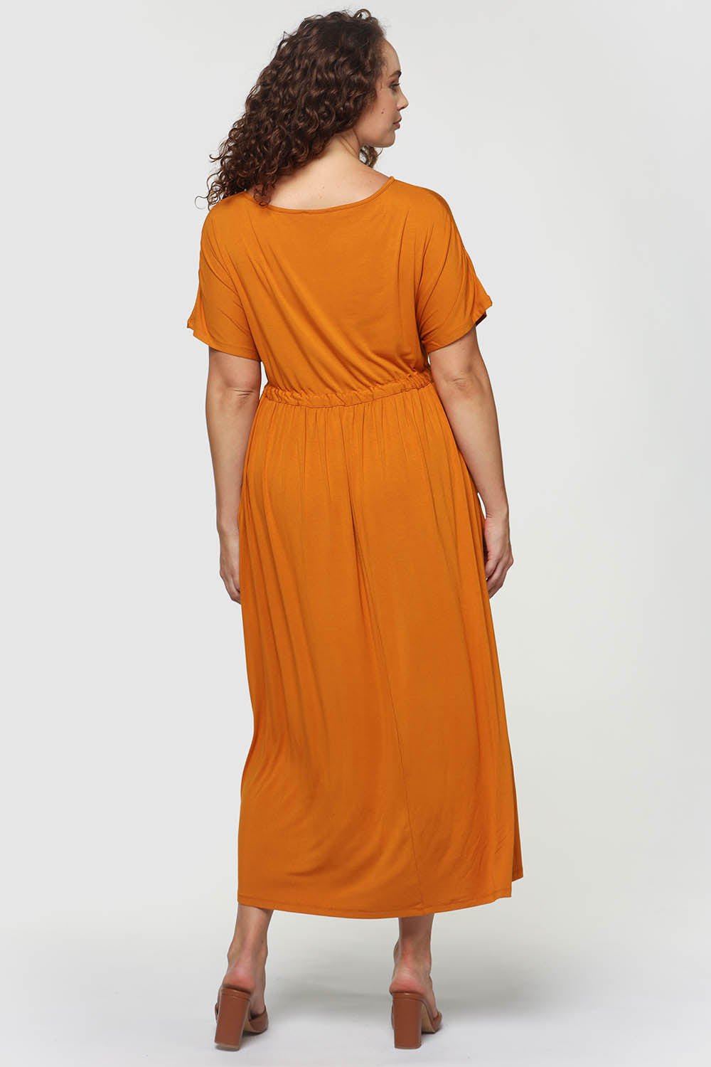 A model wearing the Mila Maxi Dress in colour Tumeric, from the back