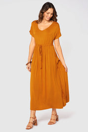A model wearing the Mila Maxi Dress in colour Tumeric, from the front, cropped image