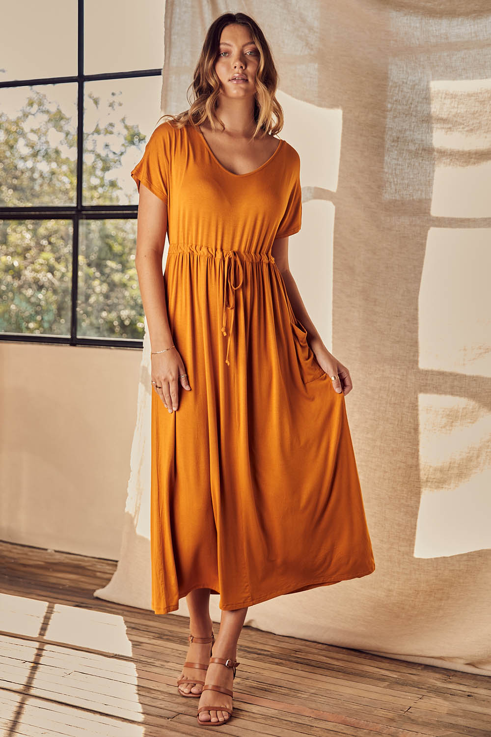 A model wearing the Mila Maxi Dress in colour Tumeric, from the front, showing the whole outfit