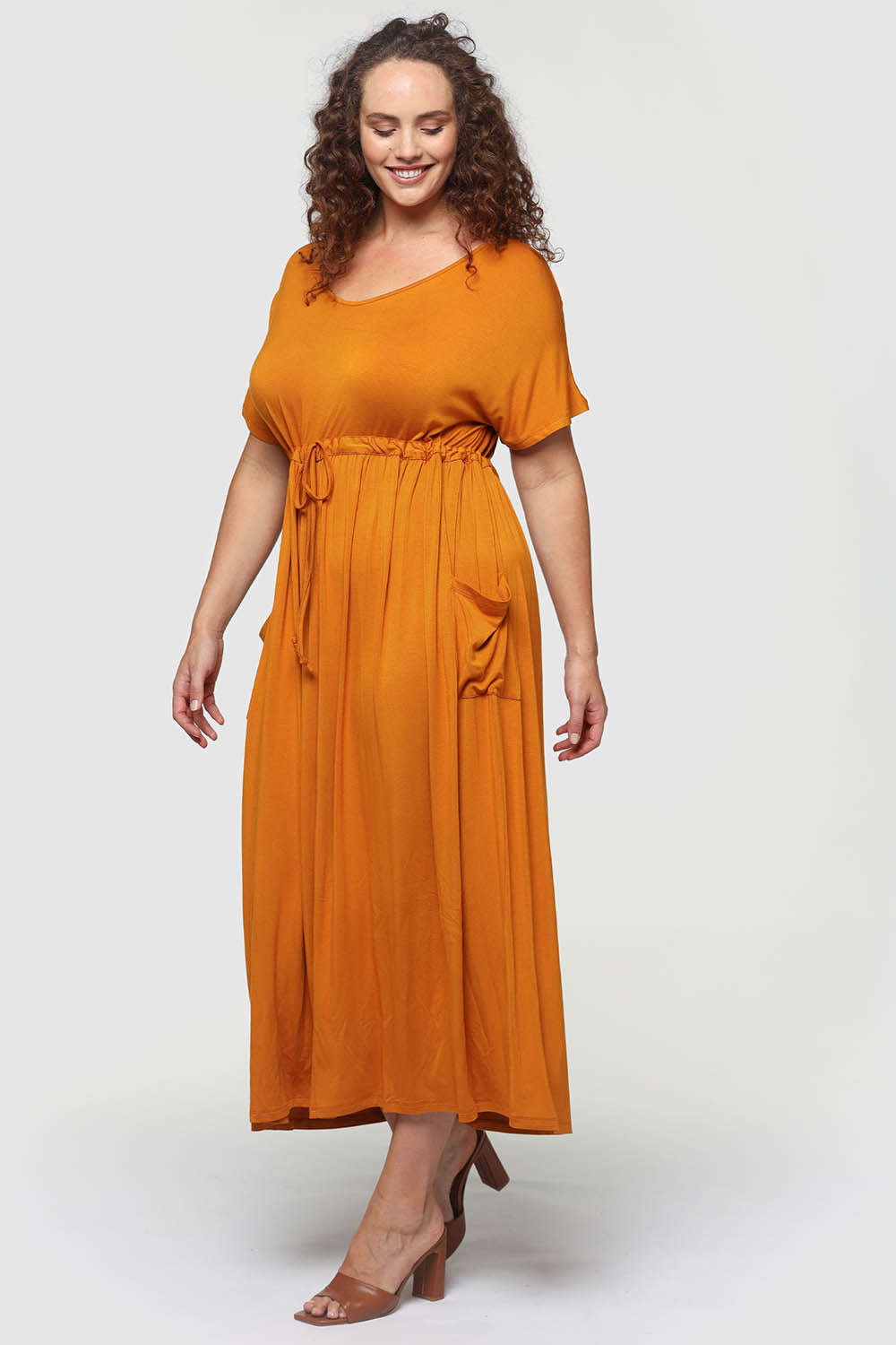 A model wearing the Mila Maxi Dress in colour Tumeric, from the front, showing the whole outfit