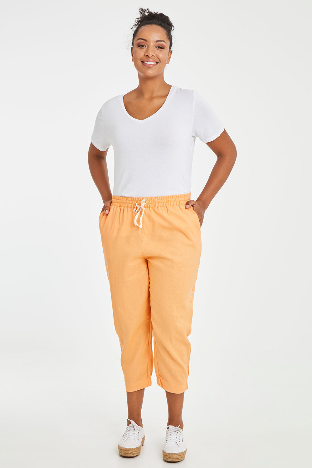 Model Noli wearing size 10 of the Lennon Pant in colour Mango, from the front, showing the whole outfit