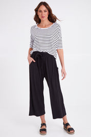 Model Madeline wearing size 10 of the Moulin Pant in colour Black (Black), from the front, showing the whole outfit