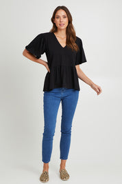 Model Madeline wearing size 10 of the Celia Tee in colour Black (Black), from the front, showing the whole outfit