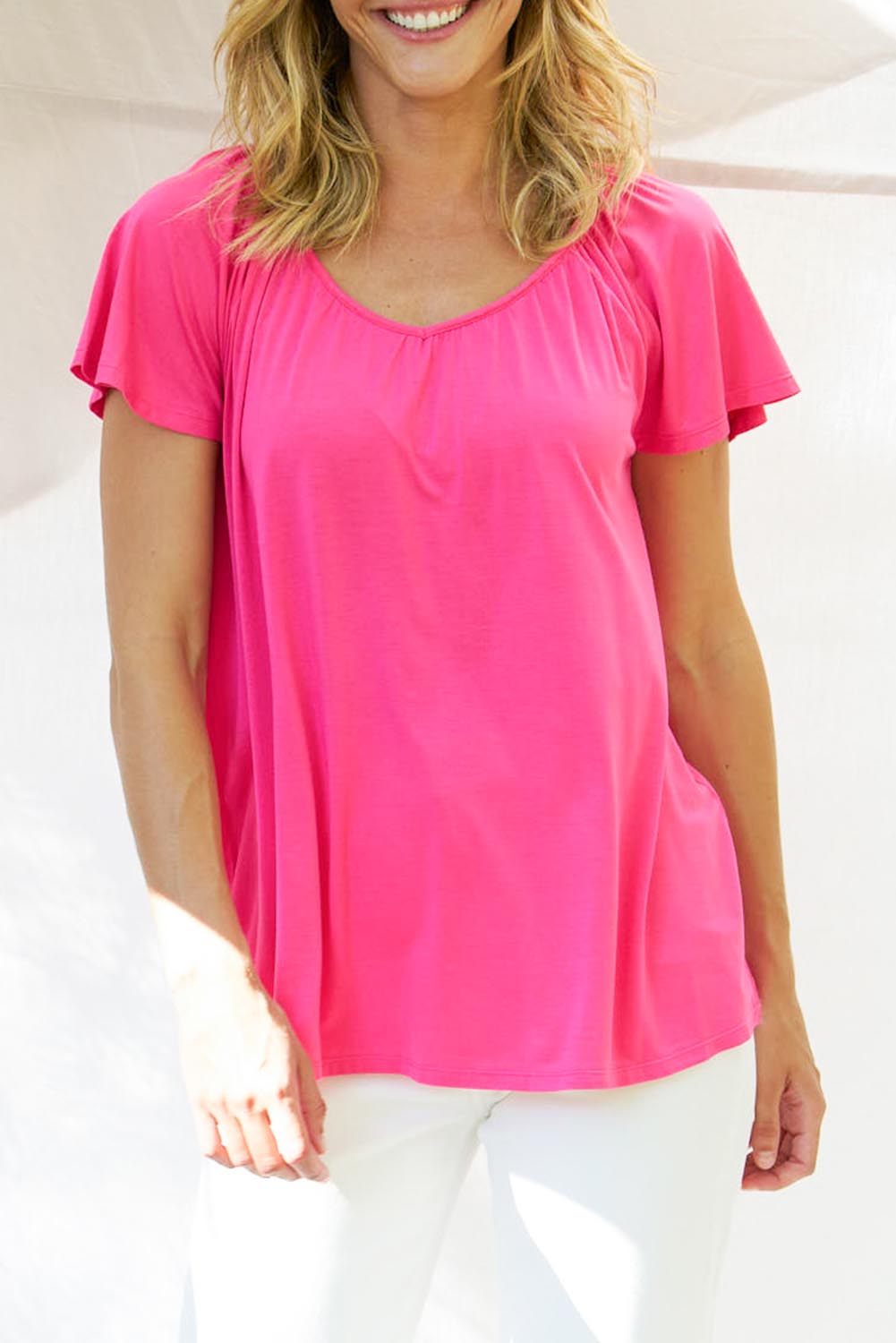 A model wearing the Coral Bamboo Shirred Tee in colour Pink (Pink), from the front, cropped image