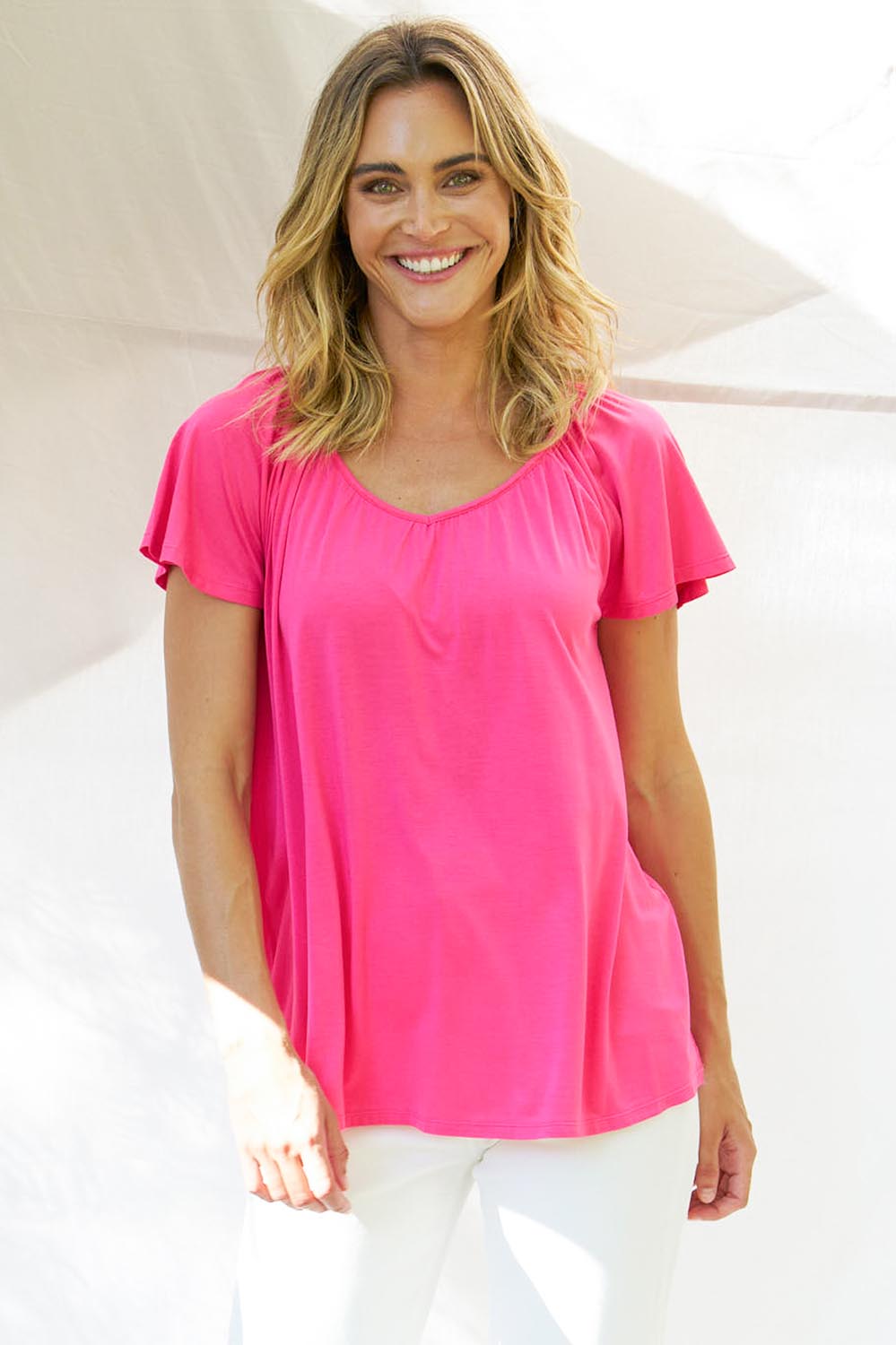 A model wearing the Coral Bamboo Shirred Tee in colour Pink (Pink), from the front, cropped image