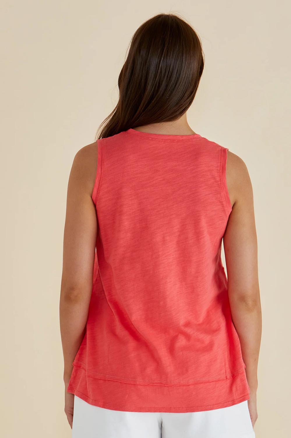 A model wearing the Mariah Cotton Tank in colour Grapefruit (Pink), from the back