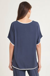 Model Madeline wearing size 10 of the Clara Tee in colour Petrol (Blue), from the back
