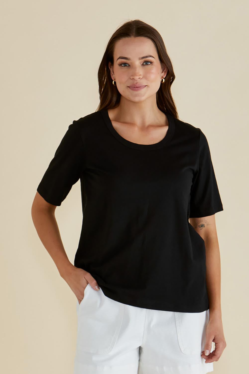 A model wearing the Riley Cotton Tee in colour Black (Black), from the front, cropped image