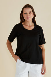 A model wearing the Riley Cotton Tee in colour Black (Black), from the front, cropped image