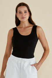 A model wearing the Emma Cotton Scoop Tank in colour Black (Black), from the front, cropped image
