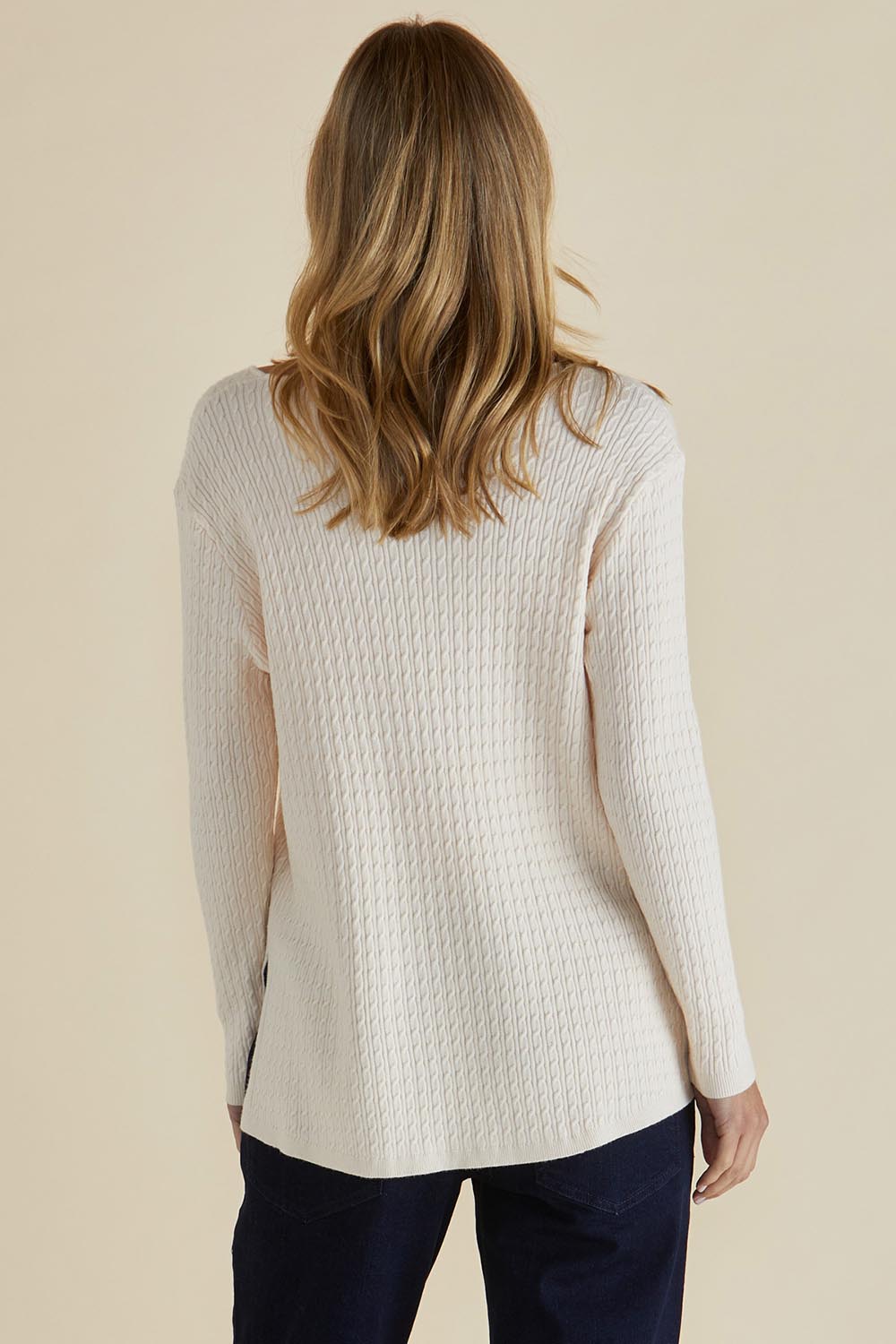 A model wearing the Cable Mini Jumper in colour Oat, from the back
