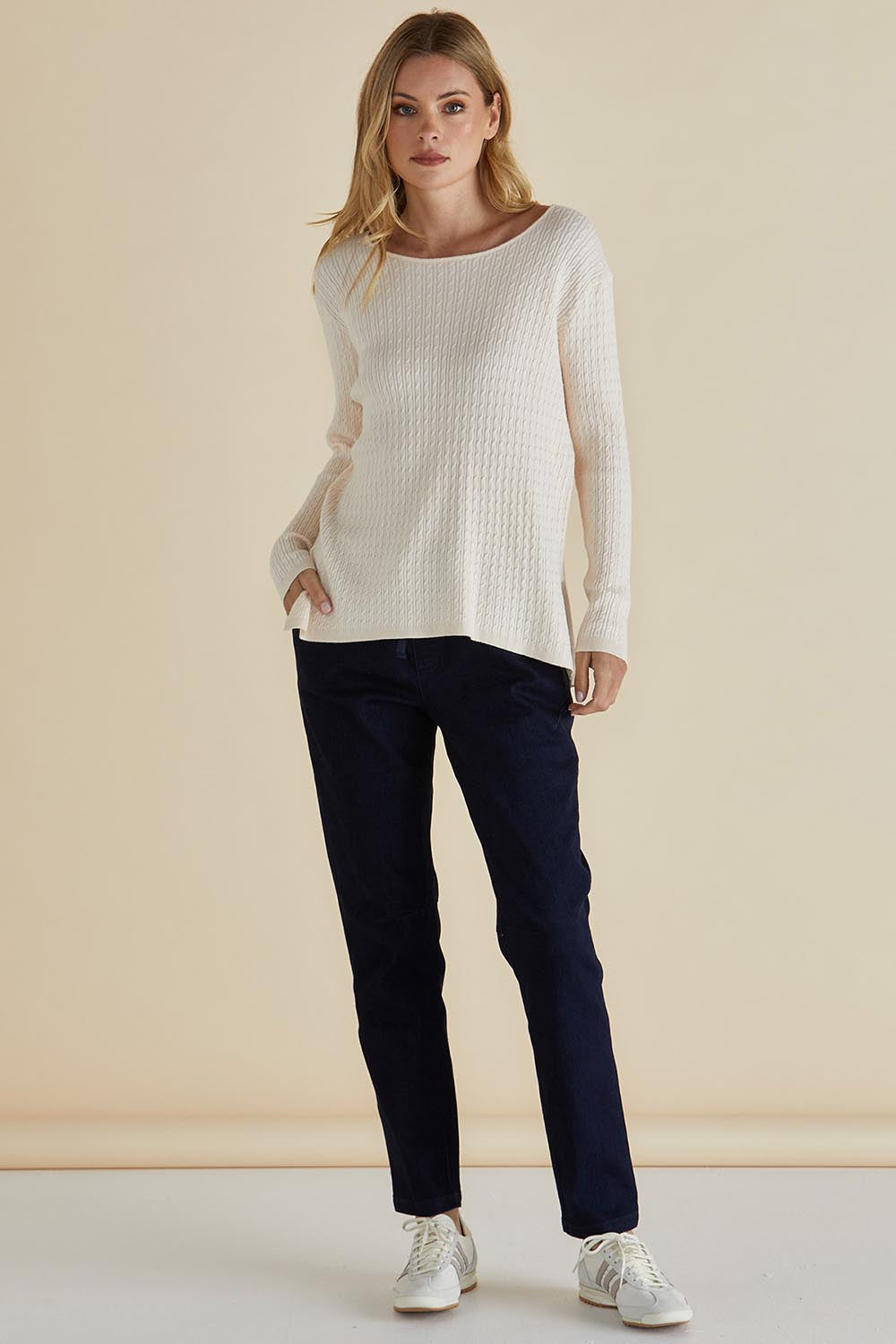 A model wearing the Cable Mini Jumper in colour Oat, from the front, showing the whole outfit