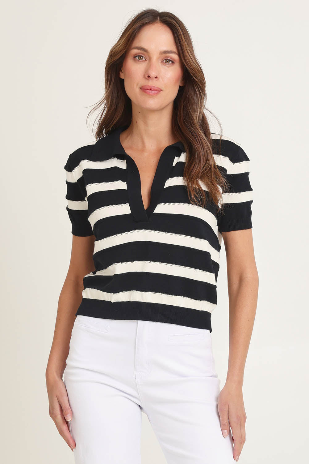 Model Madeline wearing size 10 of the Salford Cotton Knit Polo in colour Creamblk (Black), from the front, cropped image