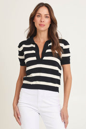 Model Madeline wearing size 10 of the Salford Cotton Knit Polo in colour Creamblk (Black), from the front, cropped image