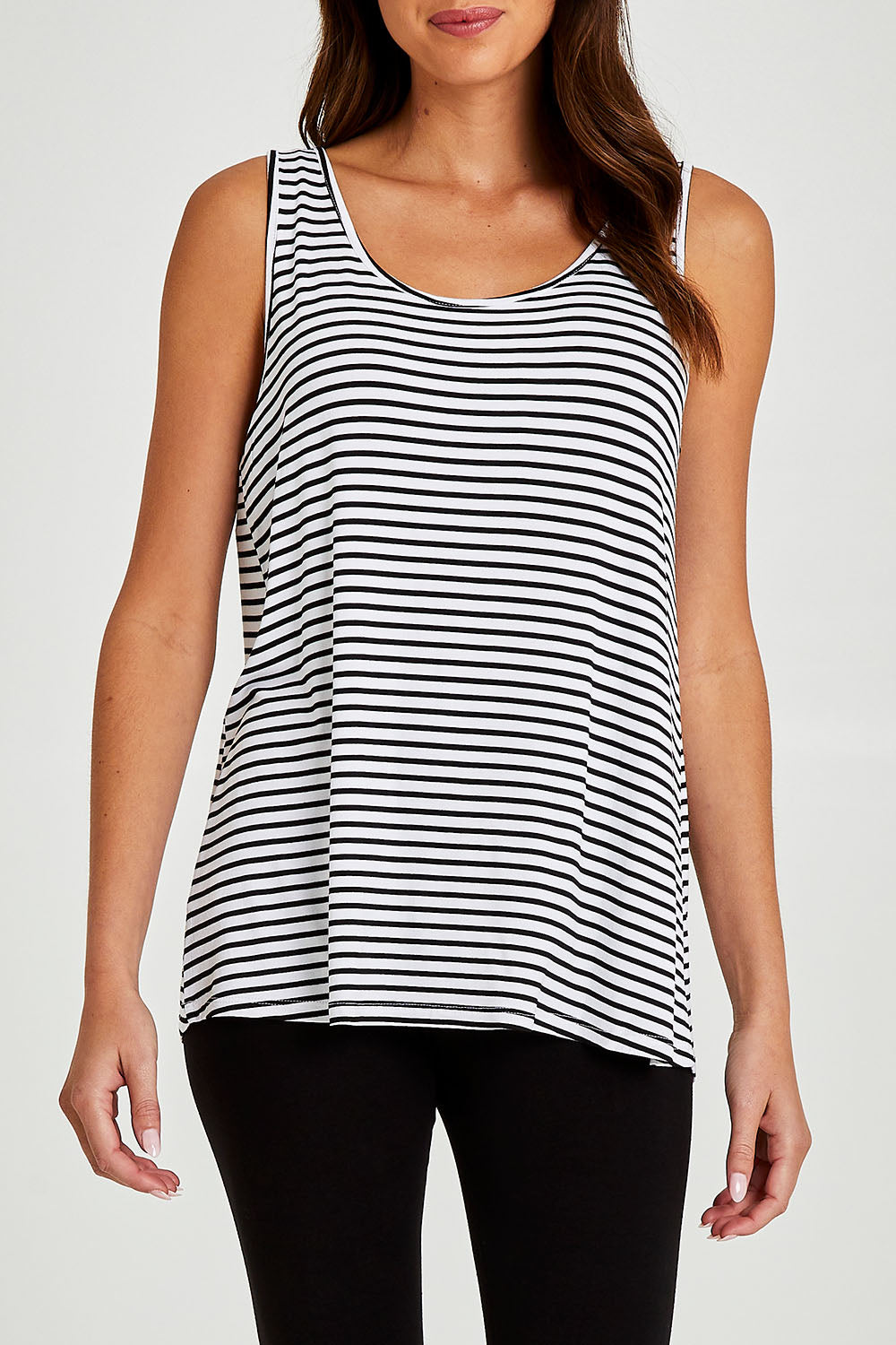 Model Madeline wearing size 10 of the Sirena Reversible Tank in colour Noirstripe (White), from the front, cropped image