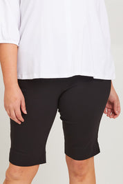 Model Poppy wearing size 16 of the Bermuda Bengaline Short in colour Black (Black), from the front, cropped image