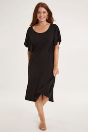 Model Sally wearing size 10 of the Tahiti Frill Dress in colour Black (Black), from the front, showing the whole outfit