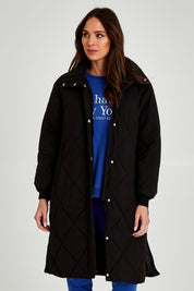 Model Madeline wearing size 10 of the Tribeca Puffer Jacket in colour Black (Black), from the front, cropped image