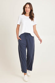 Model Madeline wearing size 10 of the Evelyn Wide Leg Jogger in colour Petrol (Blue), from the front, showing the whole outfit