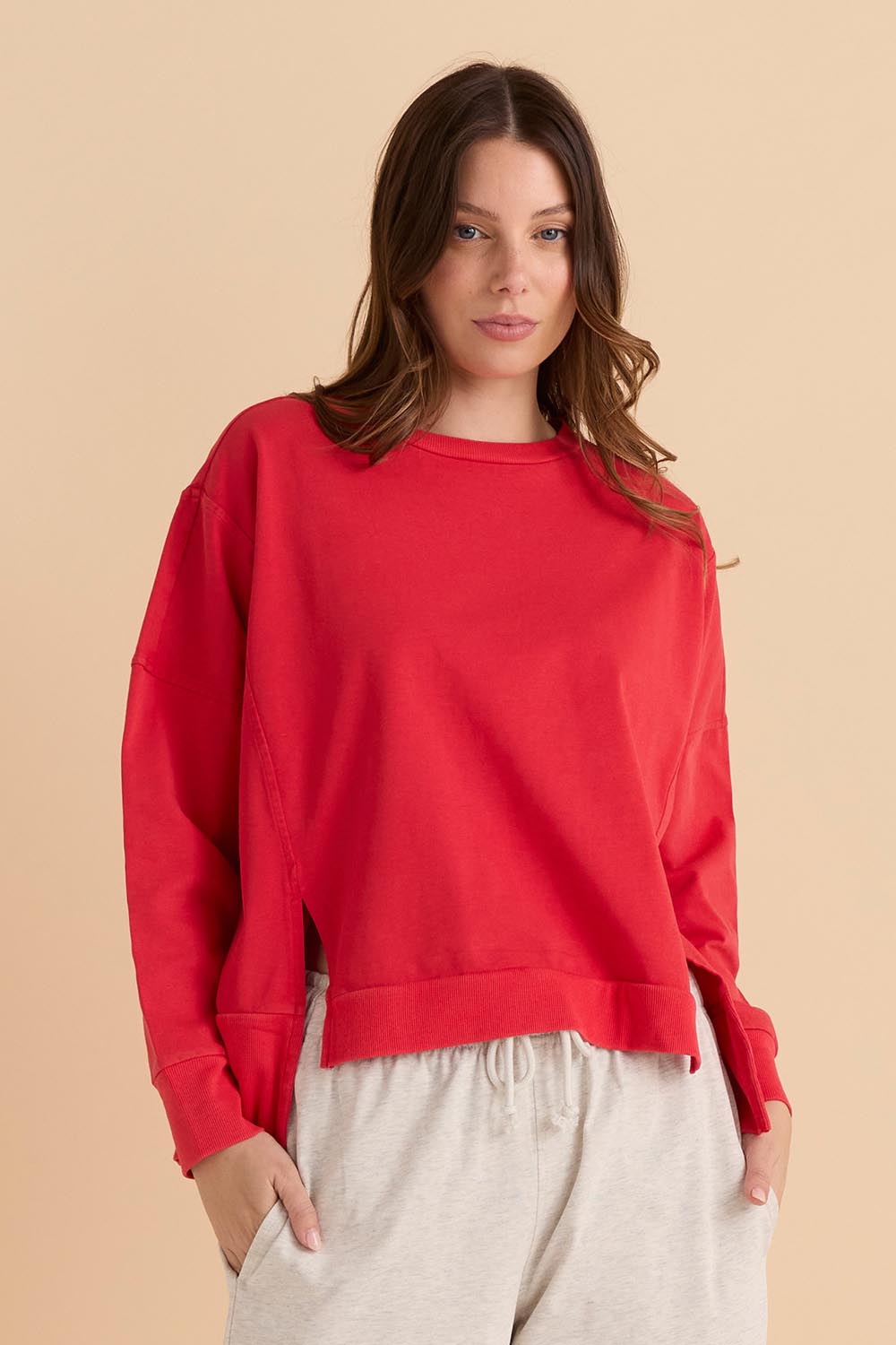 A model wearing the Iris Cotton Sweatshirt in colour Red (Red), from the front, cropped image