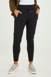 Model Olivia wearing size 10 of the Leo Ponte Jogger in colour Black (Black), from the front, cropped image