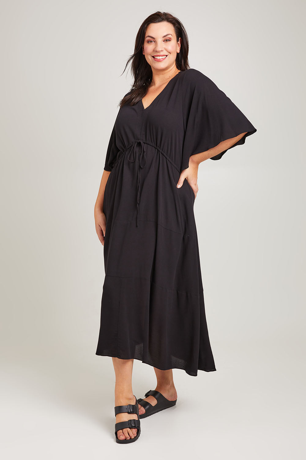Model Poppy wearing size 16 of the Saint Lucia Dress in colour Black (Black), from the front, showing the whole outfit