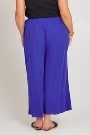 Model Poppy wearing size 16 of the Olympia Pant in colour Decoblue (Blue), from the back