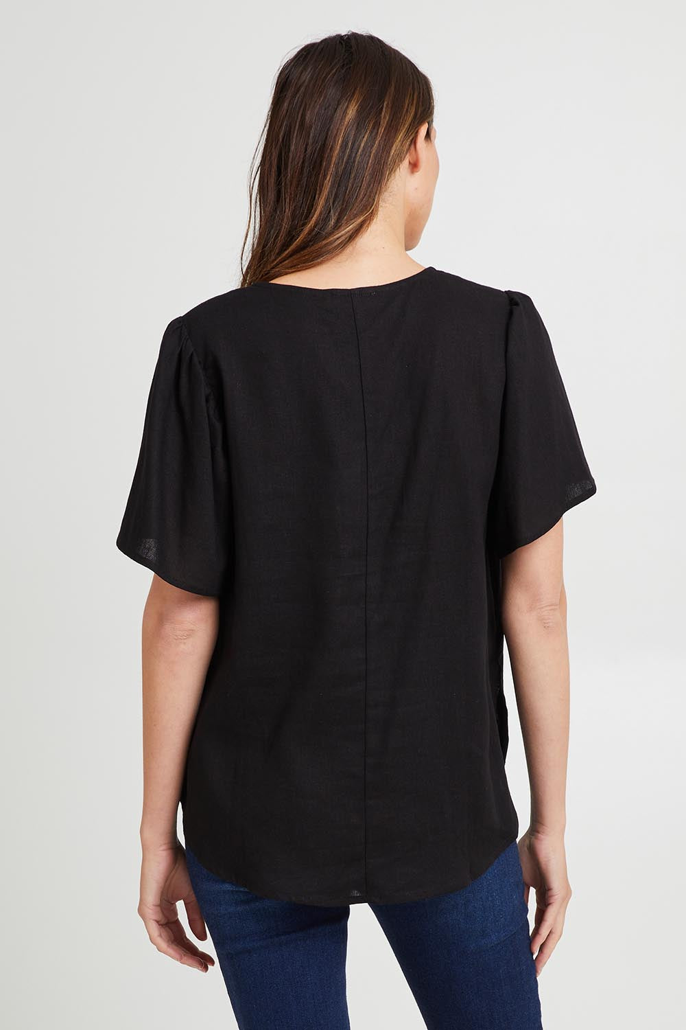 Model Madeline wearing size 10 of the Marina Linen Blouse in colour Black (Black), from the back