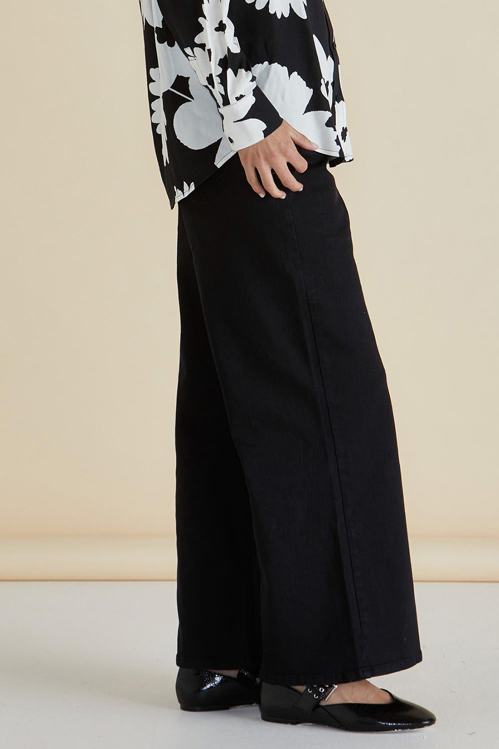 A model wearing the Wilma Wide Leg Jean in colour Black (Black), from the front, cropped image