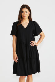 A model wearing the Florence Tiered Dress in colour Black (Black), from the front, cropped image