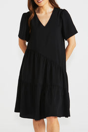 A model wearing the Florence Tiered Dress in colour Black (Black), from the front, cropped image
