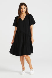 A model wearing the Florence Tiered Dress in colour Black (Black), from the front, showing the whole outfit