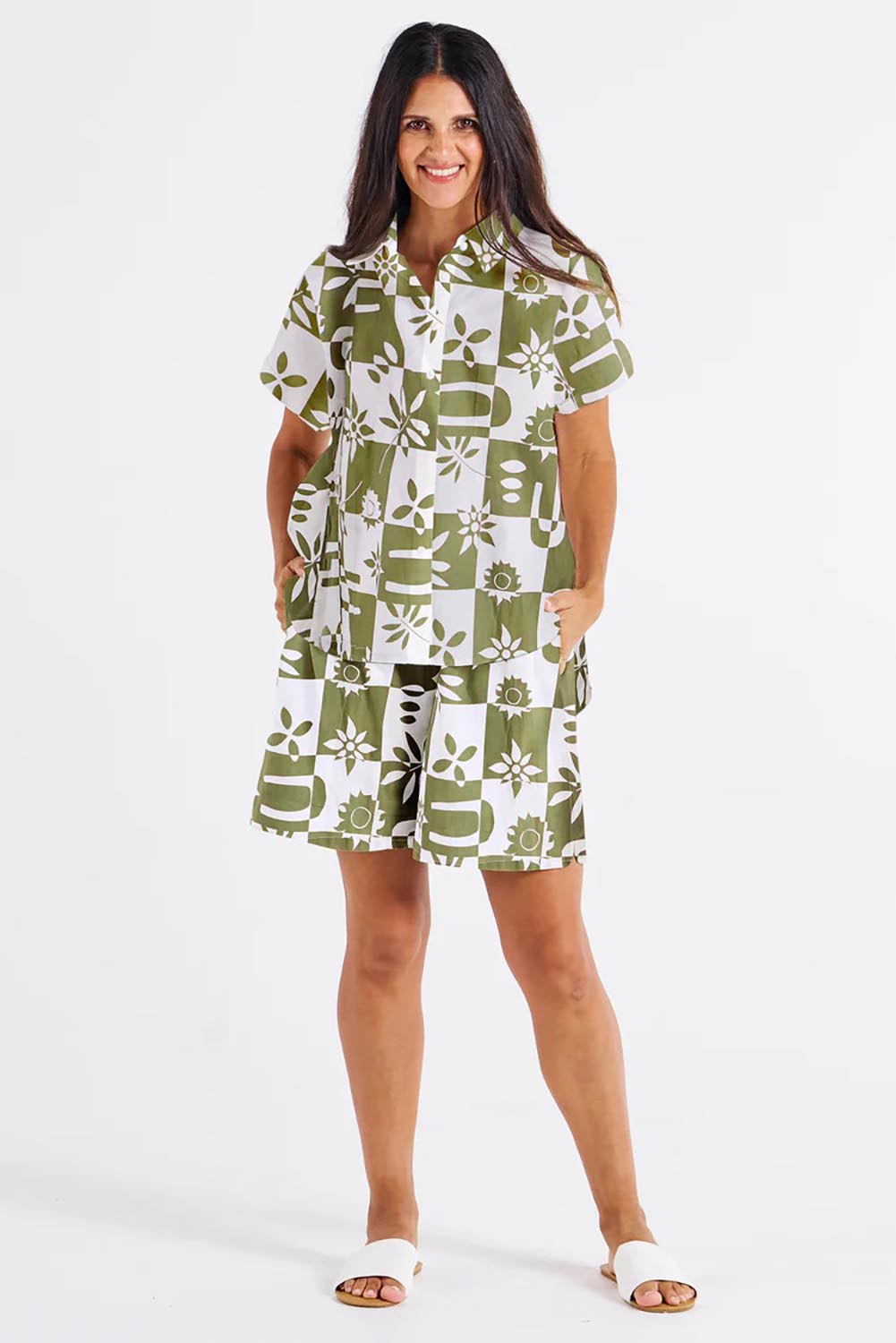 A model wearing the Mara Cotton Shirt in colour Geofloral (Green), from the front, showing the whole outfit