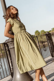 A model wearing the Elianna Dress in colour Pistachio (Green), from the front, showing the whole outfit