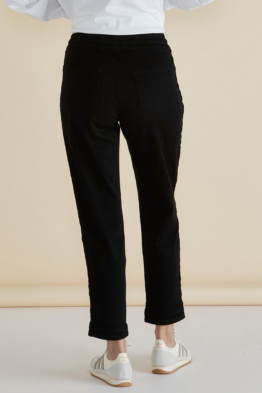A model wearing the Harlow Denim Jogger in colour Blacklurex (Black), from the back