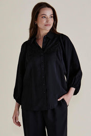 A model wearing the Rosalind Shirt in colour Black (Black), from the front, cropped image