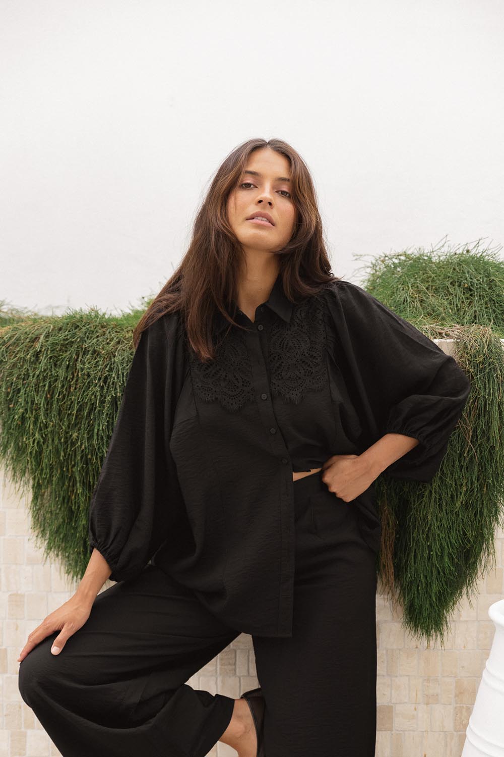 A model wearing the Rosalind Shirt in colour Black (Black), from the front, showing the whole outfit